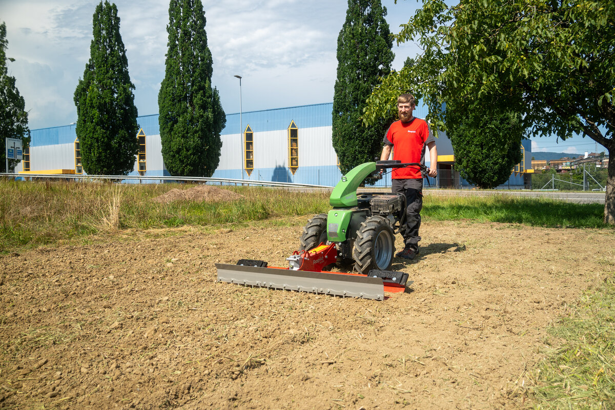 Ein Mann bearbeitet den Boden mit der Planieregge und dem KIPOS Einachser - der Gartenbauprofi